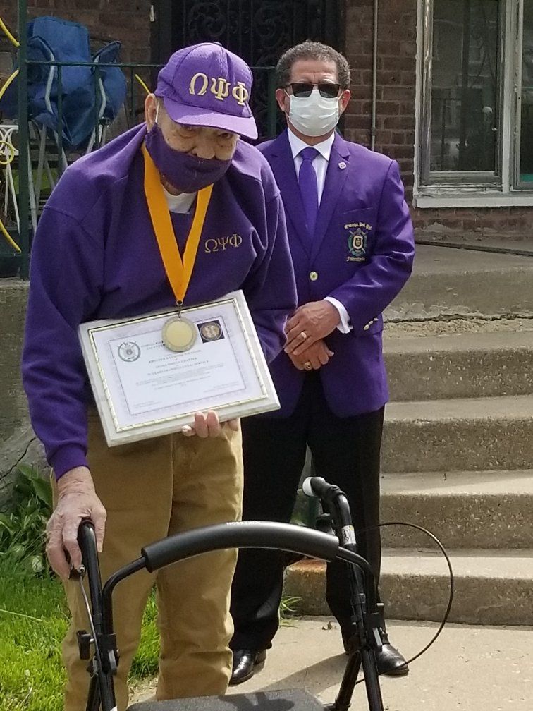 A man wearing a mask and a purple hat is holding a certificate.
