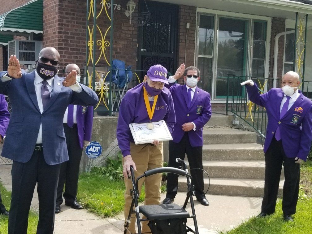 A group of men in purple suits are standing in front of a house.