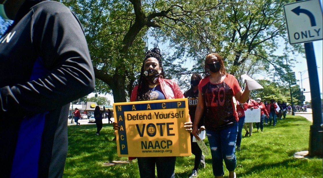A group of people are walking down a street holding signs.