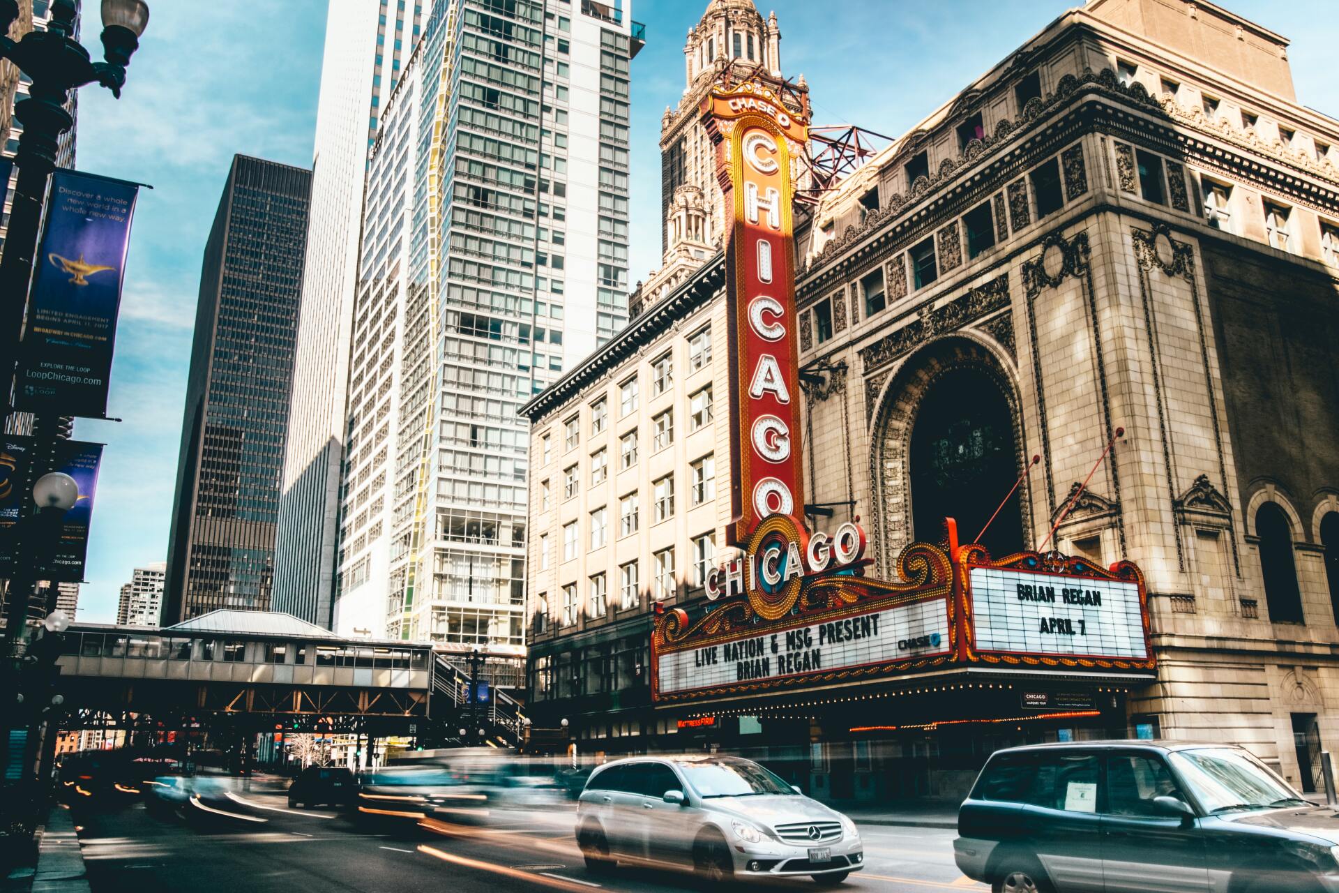 A car is driving down a city street in front of a chicago theater.