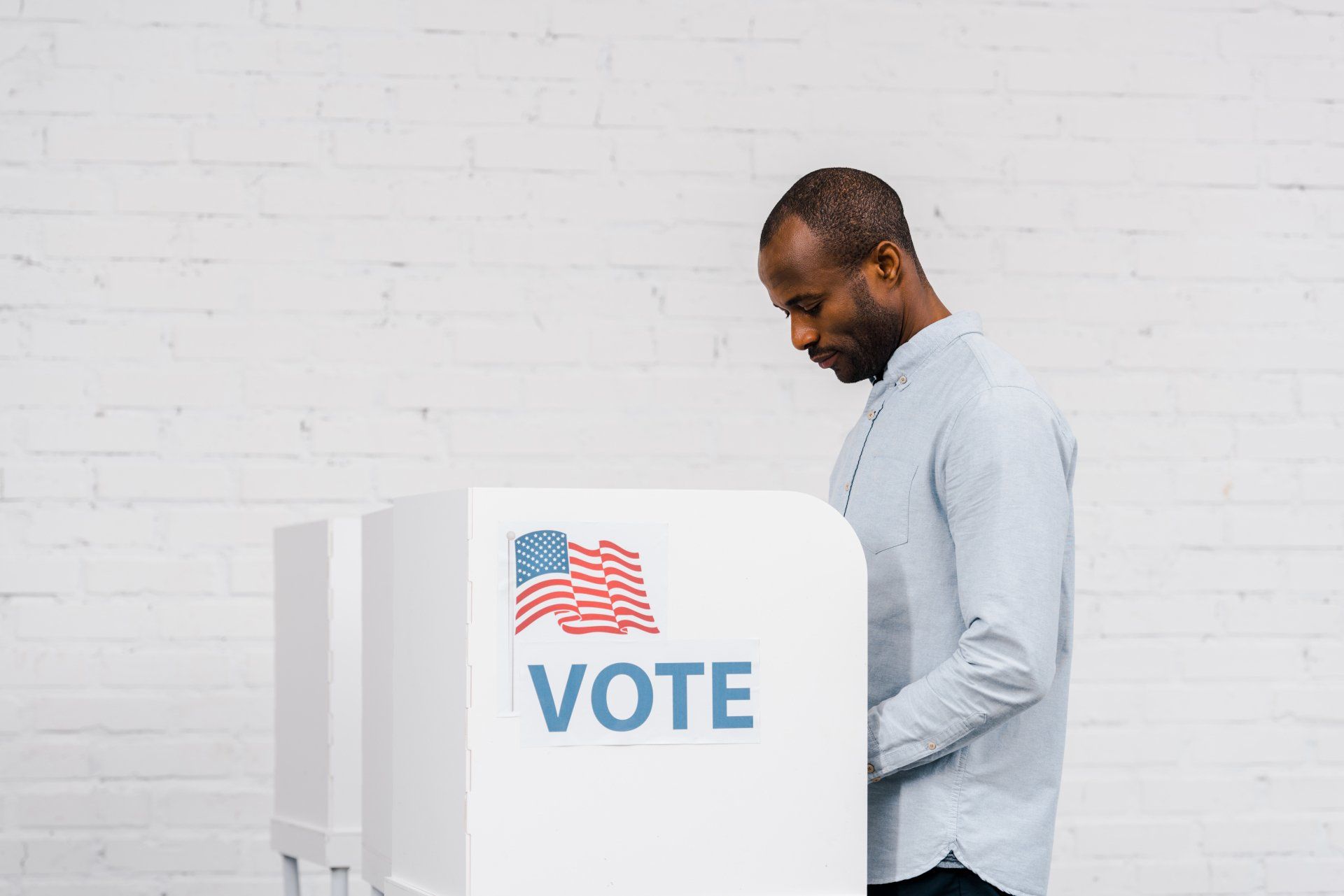 A man is voting in a voting booth.