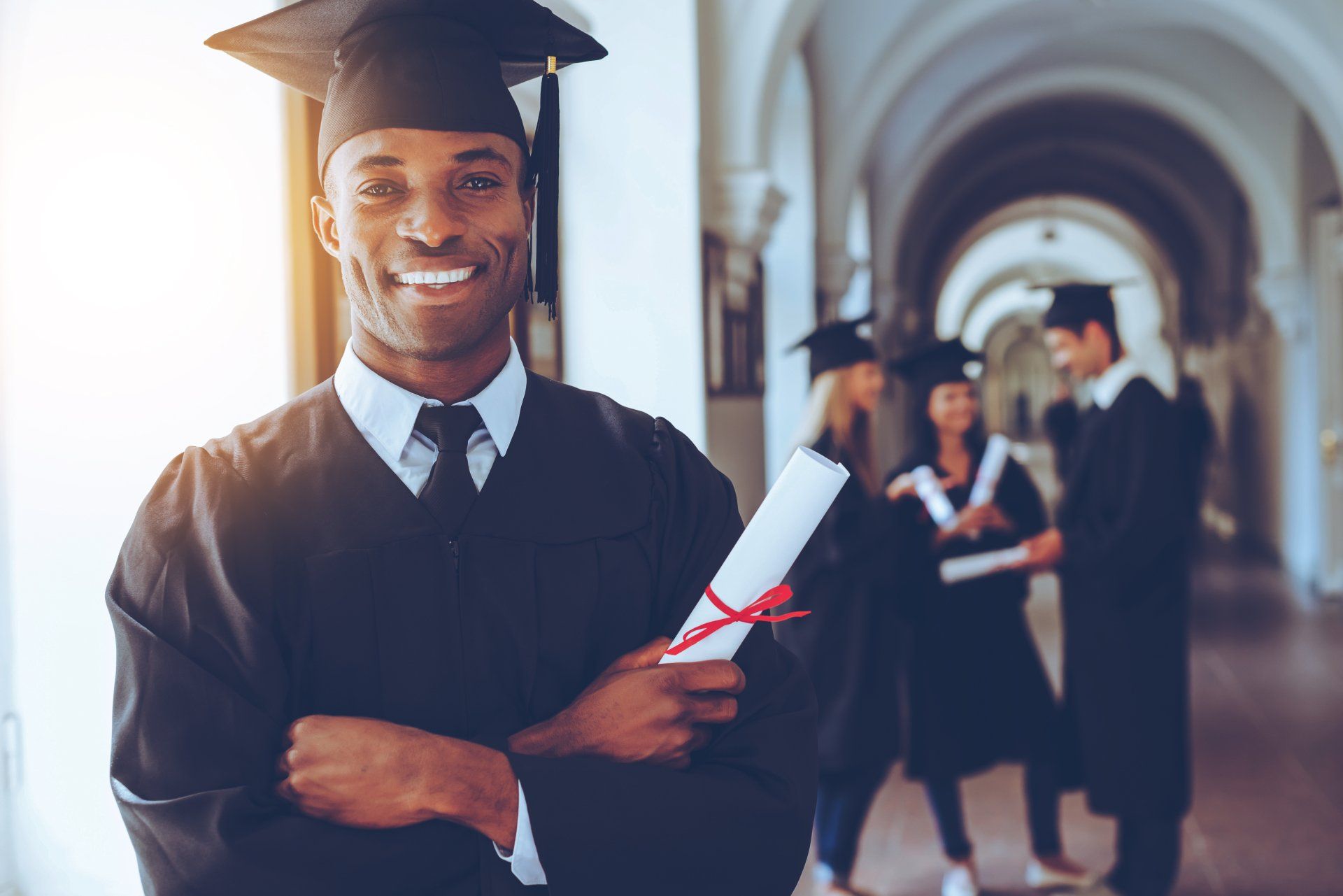 A man in a graduation cap and gown is holding a diploma.