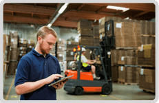 Man holding a clip board with a forklift truck in the background 