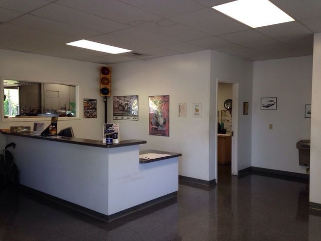 Reception area with white walls, a dark counter, and traffic light. Dark floor, doorway to an office.