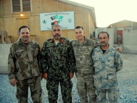 Four soldiers posing for a picture in front of a sign that says afghanistan