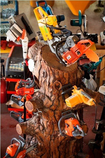 Motoseghe esposte su una scultura in legno intagliato, probabilmente in un laboratorio. Vari colori, utensili elettrici.