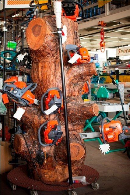 Motoseghe esposte su un grande espositore a forma di tronco d'albero all'interno di un negozio di ferramenta.