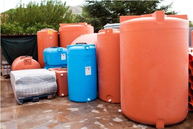 Raccolta di serbatoi di plastica arancioni e blu per lo stoccaggio dell'acqua all'aperto.