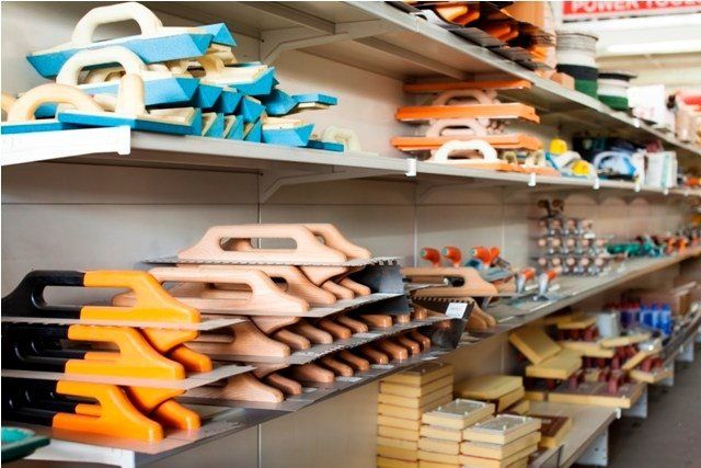 Scaffali di un negozio pieni di cazzuole e altri attrezzi da costruzione di vari colori.