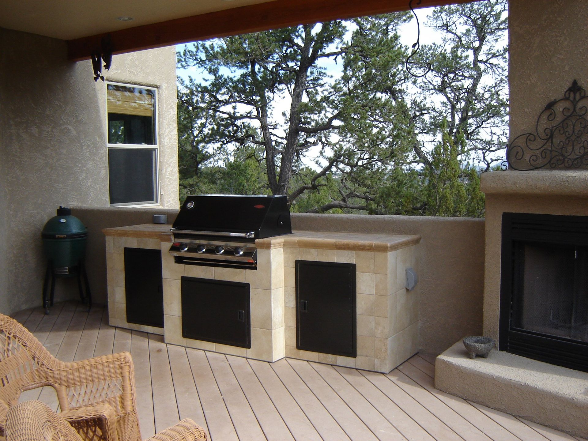 A patio with a grill and a fireplace with trees in the background