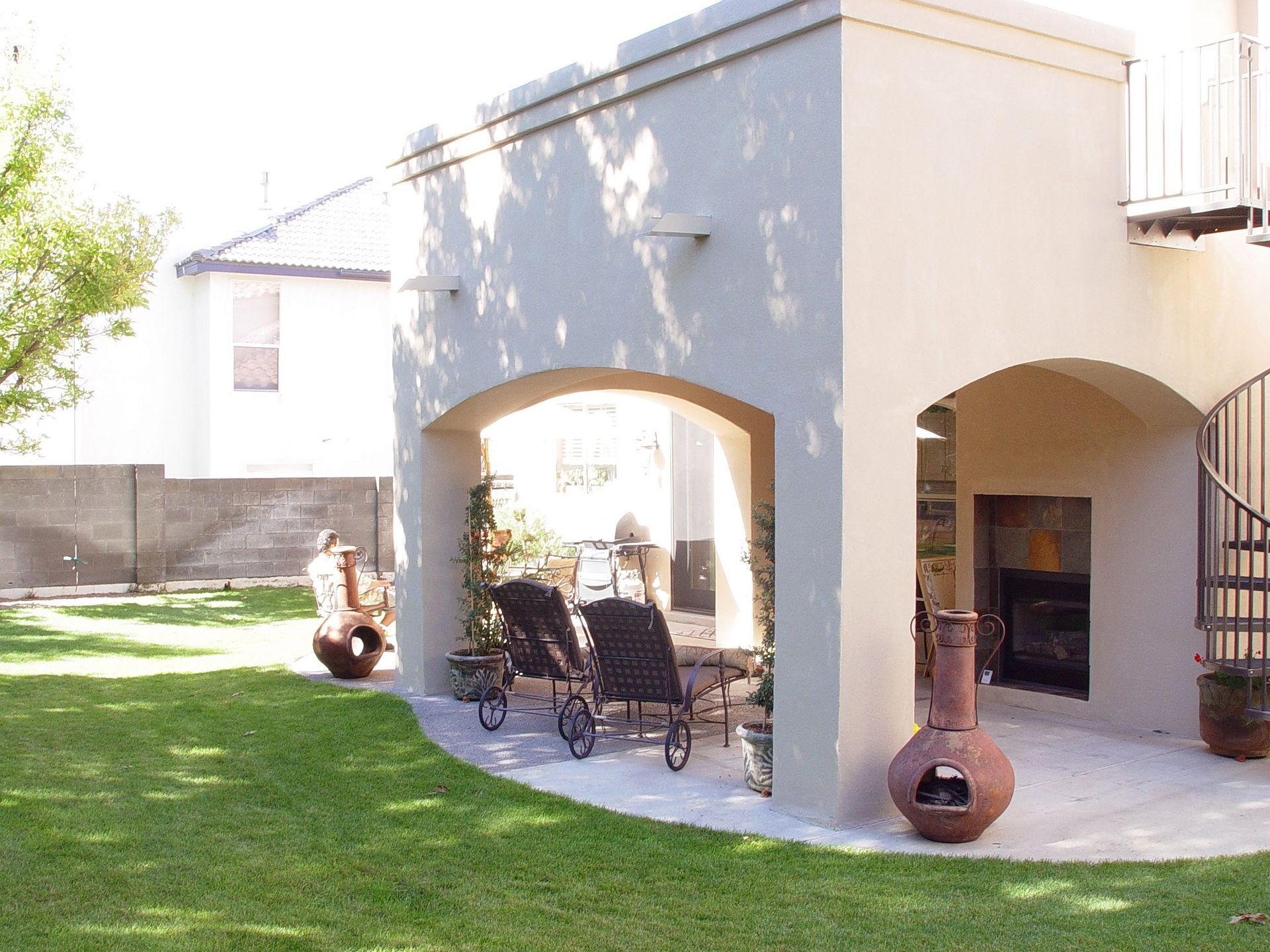 A patio with chairs and a fireplace in the backyard of a house