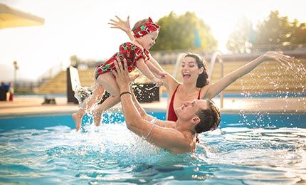 Family Happily Swimming In A Pool