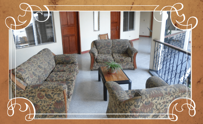 Sala de estar con sofás estampados, sillones y una mesa de centro enmarcada por un borde decorativo.