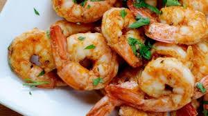 Plato de gambas cocidas adornado con hierbas picadas, vista de cerca.