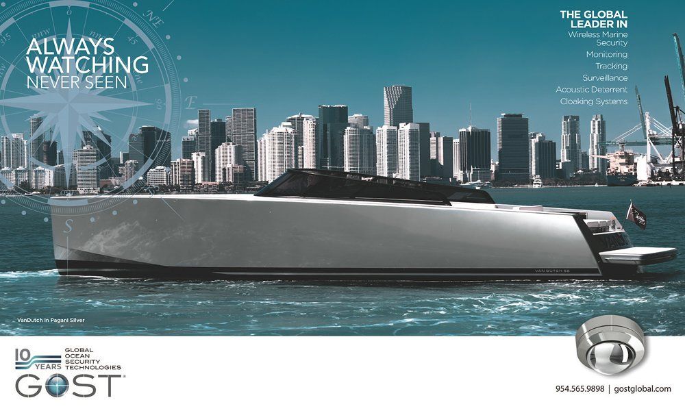 A boat is floating on top of a body of water in front of a city skyline.