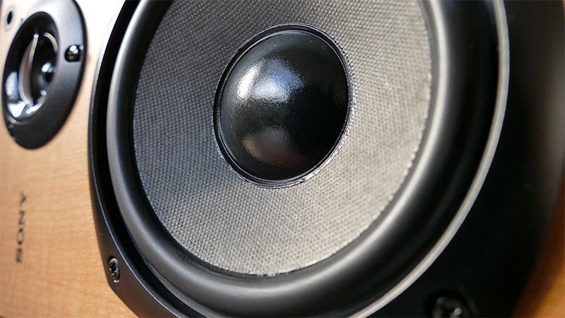 A close up of a speaker on a wooden surface