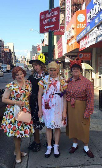 4 actors dressed in colorful and wild costumes standing on a street corner