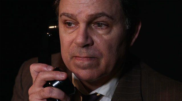 Close-up of Bernie, looking unhappy, talking on phone