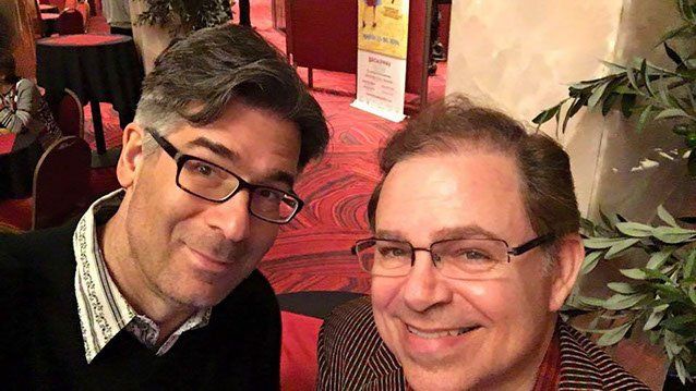 2 men in glasses smiling for picture