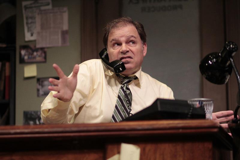 Man sitting at desk on phone with right hand up