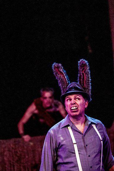 Man wearing costume of purple shirt, white suspenders, hat and long rabbit ears