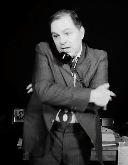 Bernie, in black and white, talking on phone with arms across his chest