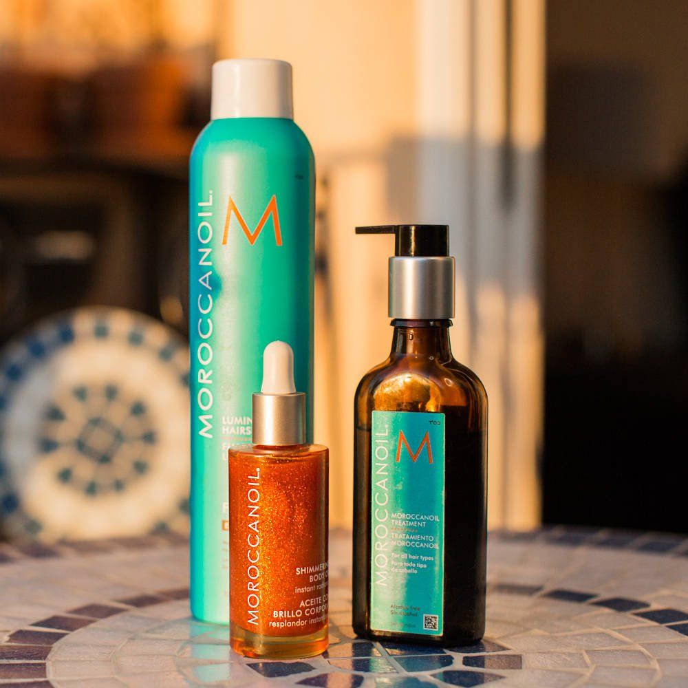 Moroccanoil hair products: oil, foam, and hair serum on a mosaic table.