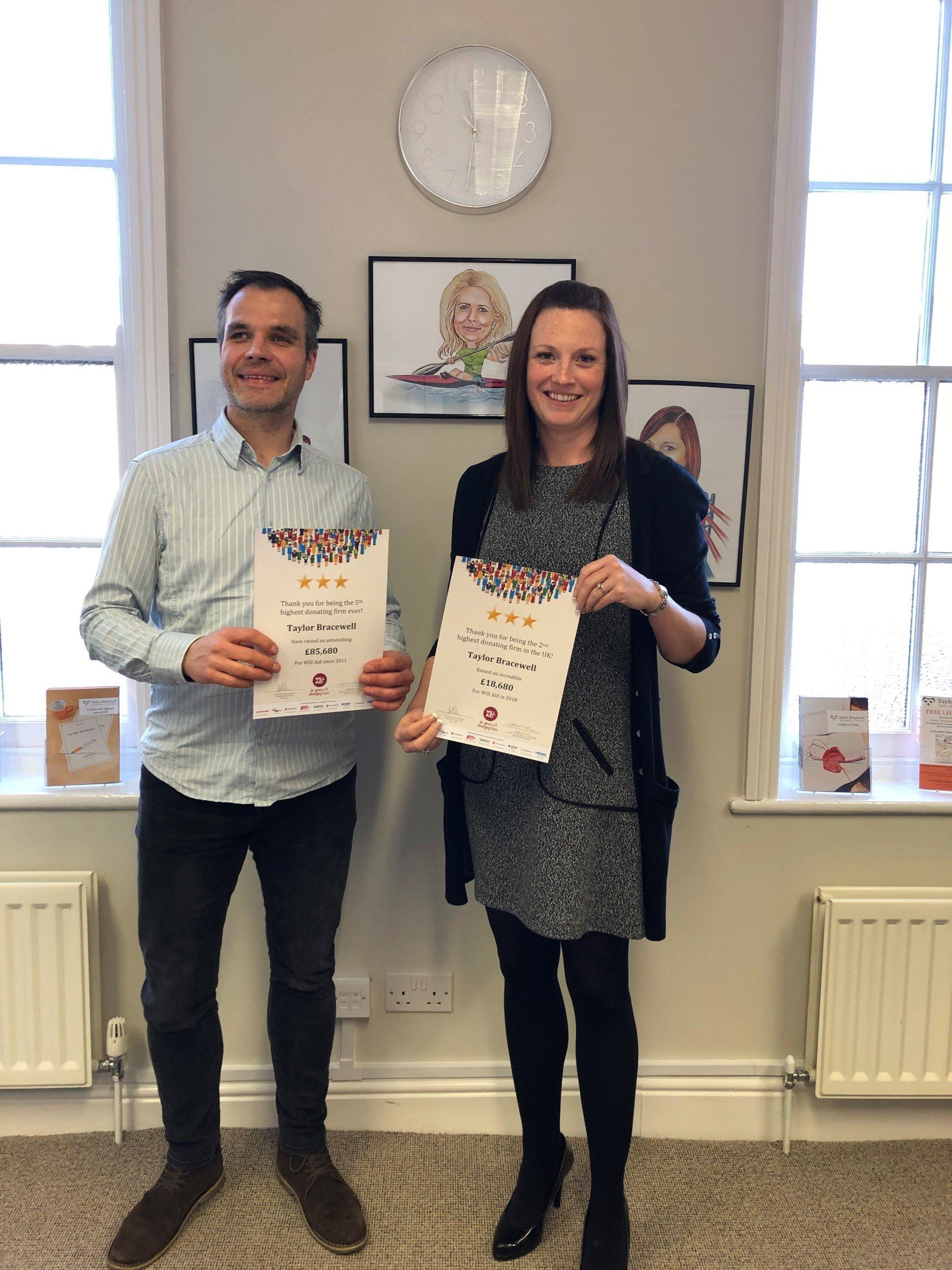 A man and a woman are standing next to each other in a room holding certificates.