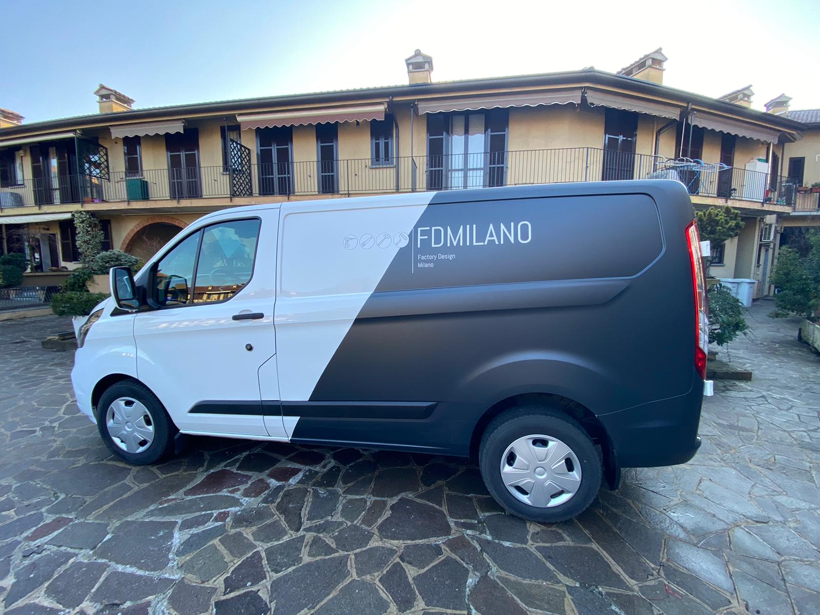 Un furgone bianco e nero è parcheggiato davanti a un edificio.