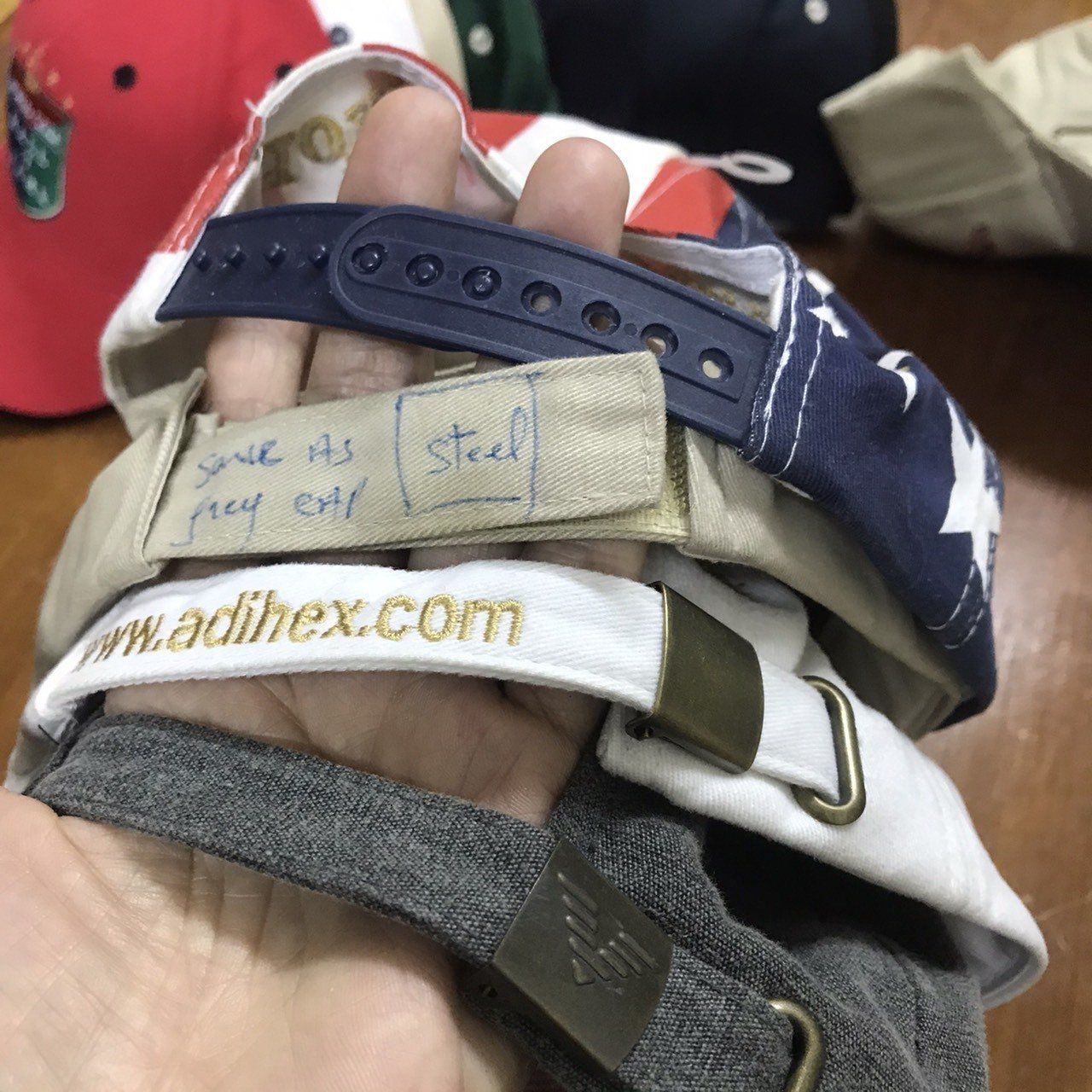 A person is holding a stack of hats including one that says steel