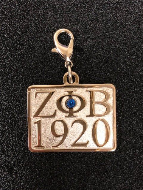 A gold pendant with the year 1920 on it is sitting on a black surface.