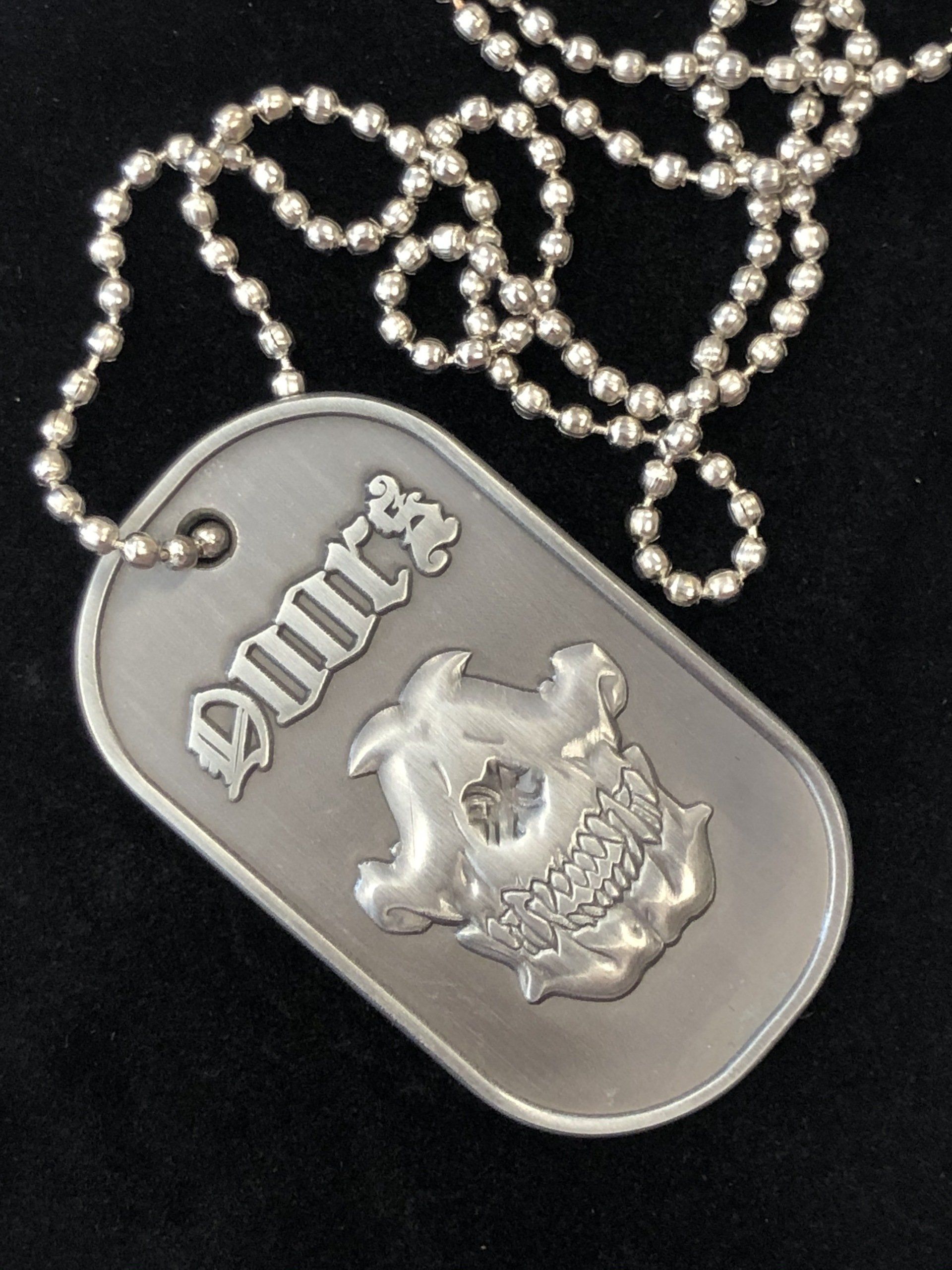 A silver dog tag with the word dmrs on it