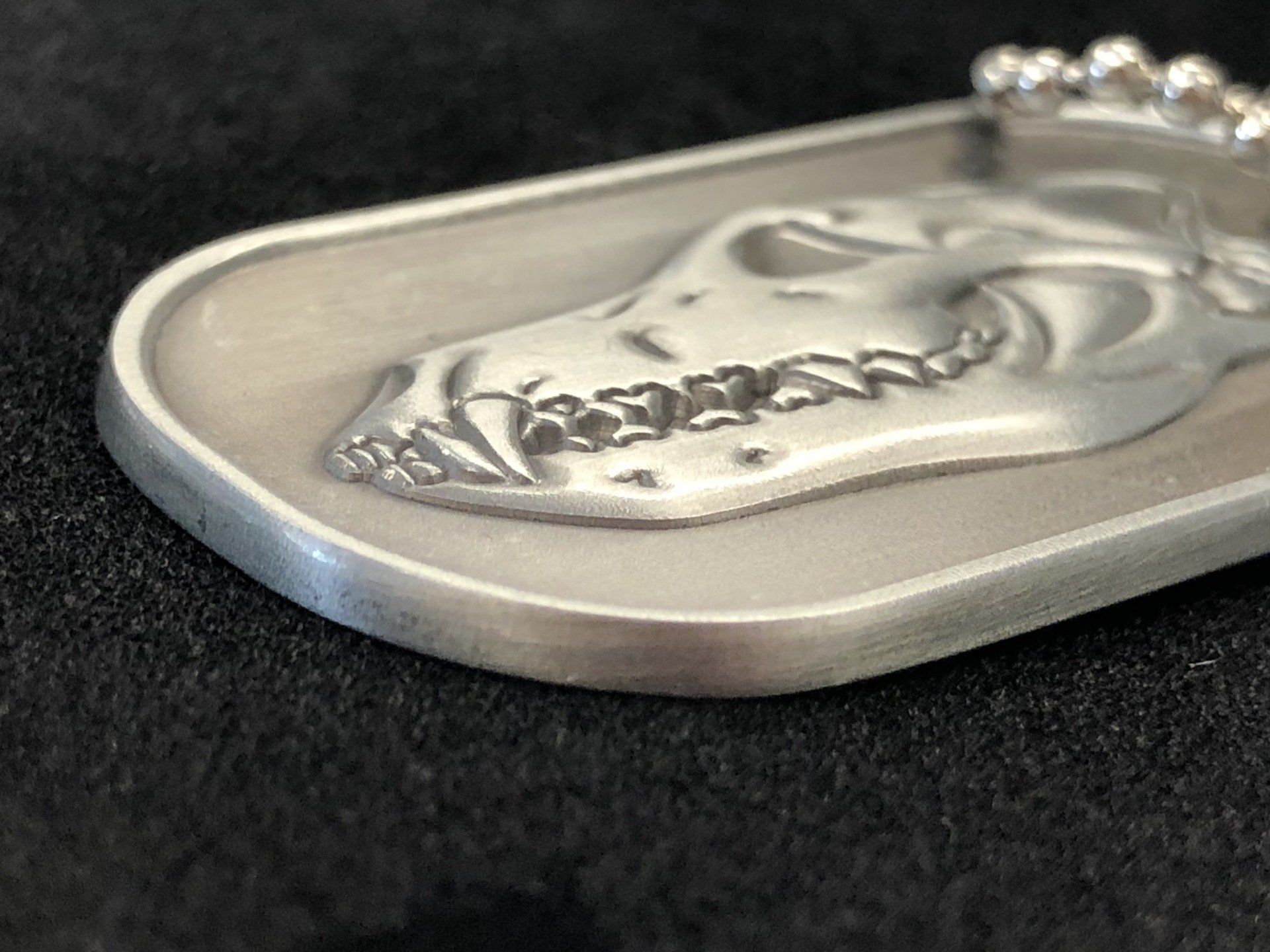 A close up of a dog tag with a skull on it