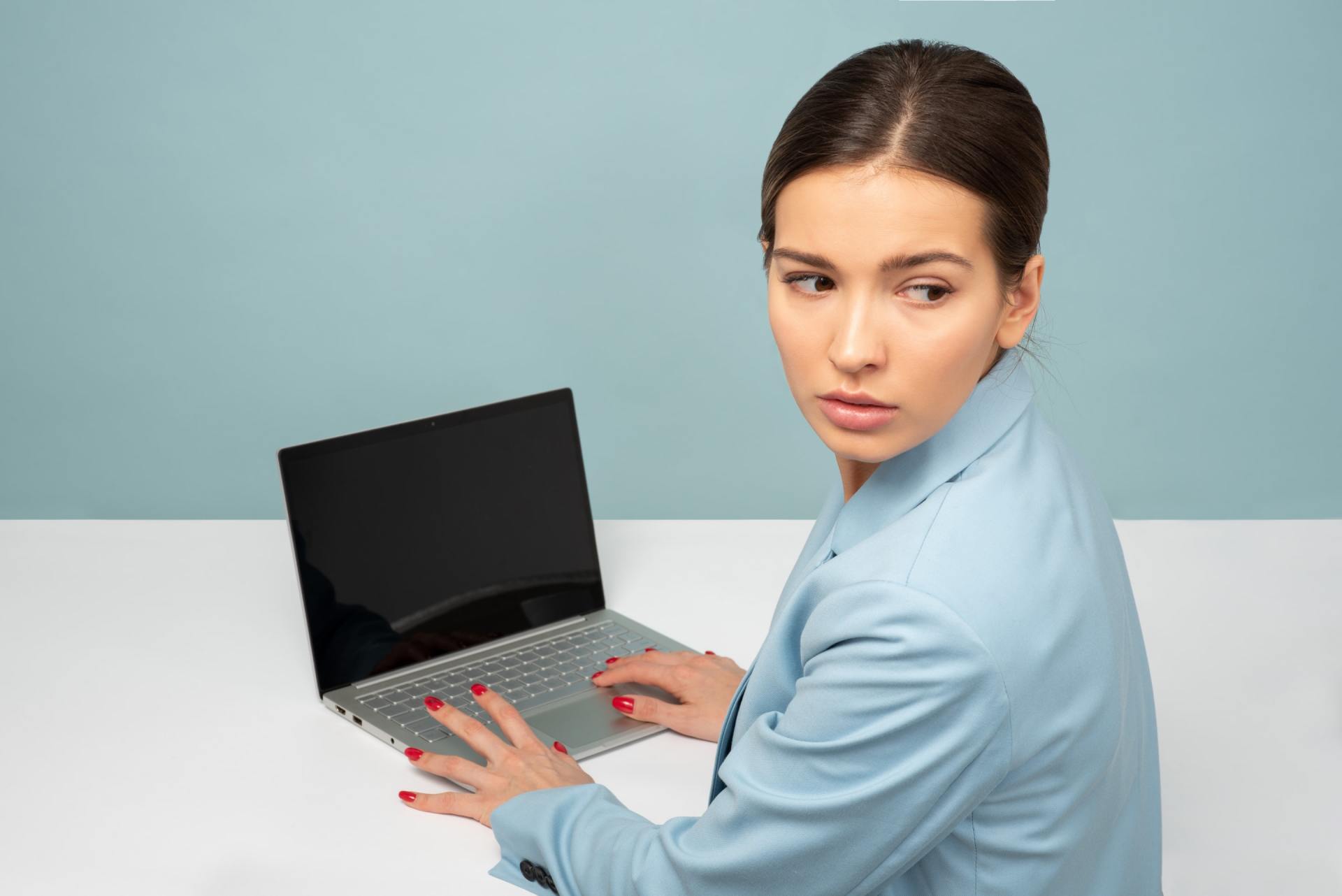 A woman is sitting at a desk using a laptop computer.
