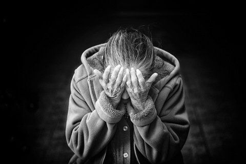 An elderly person closing eyes with hands