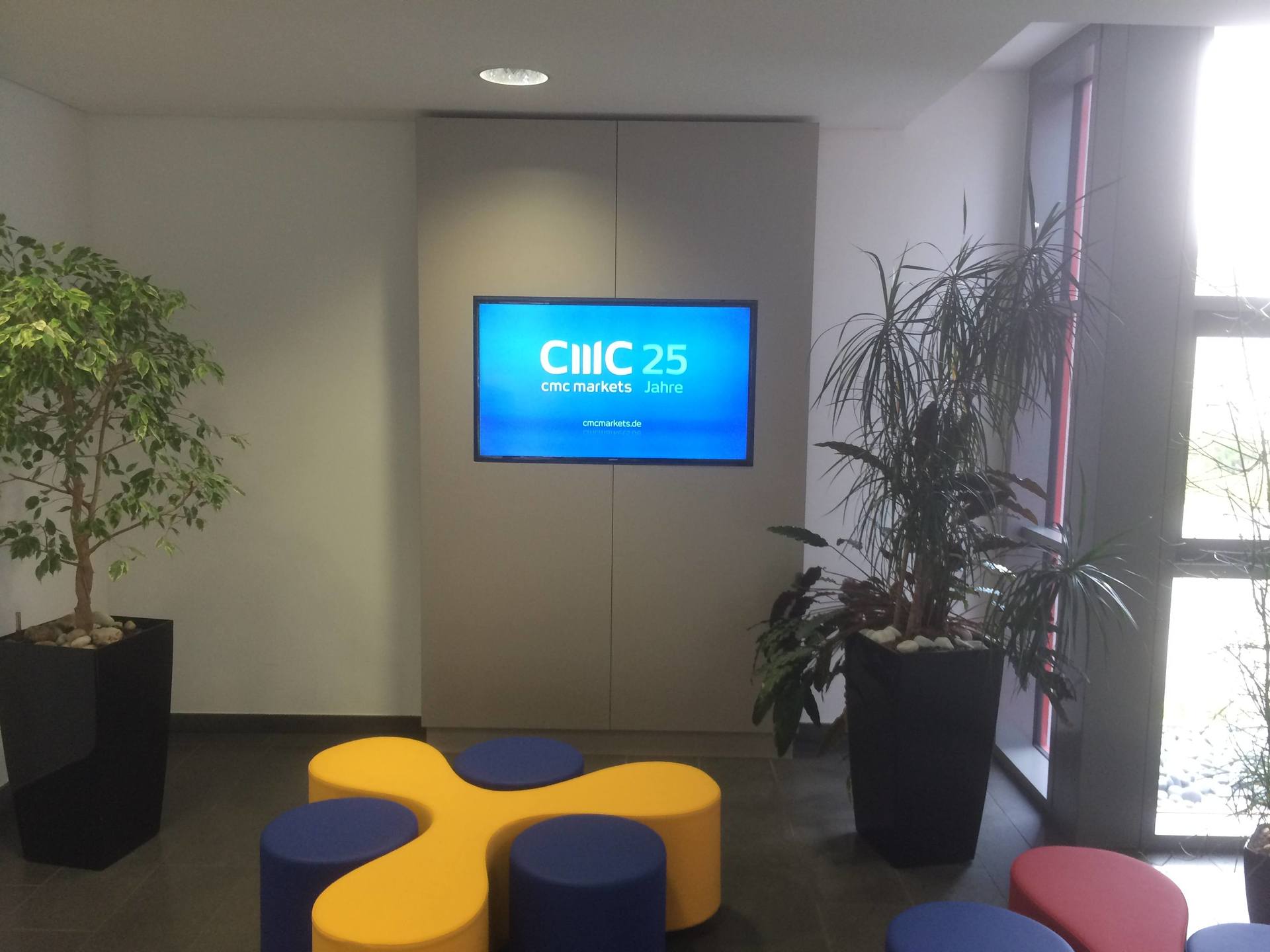 Eine Lobby mit einem an der Wand montierten Fernseher, auf dem „CIIC 25“ angezeigt wird, flankiert von zwei großen 
