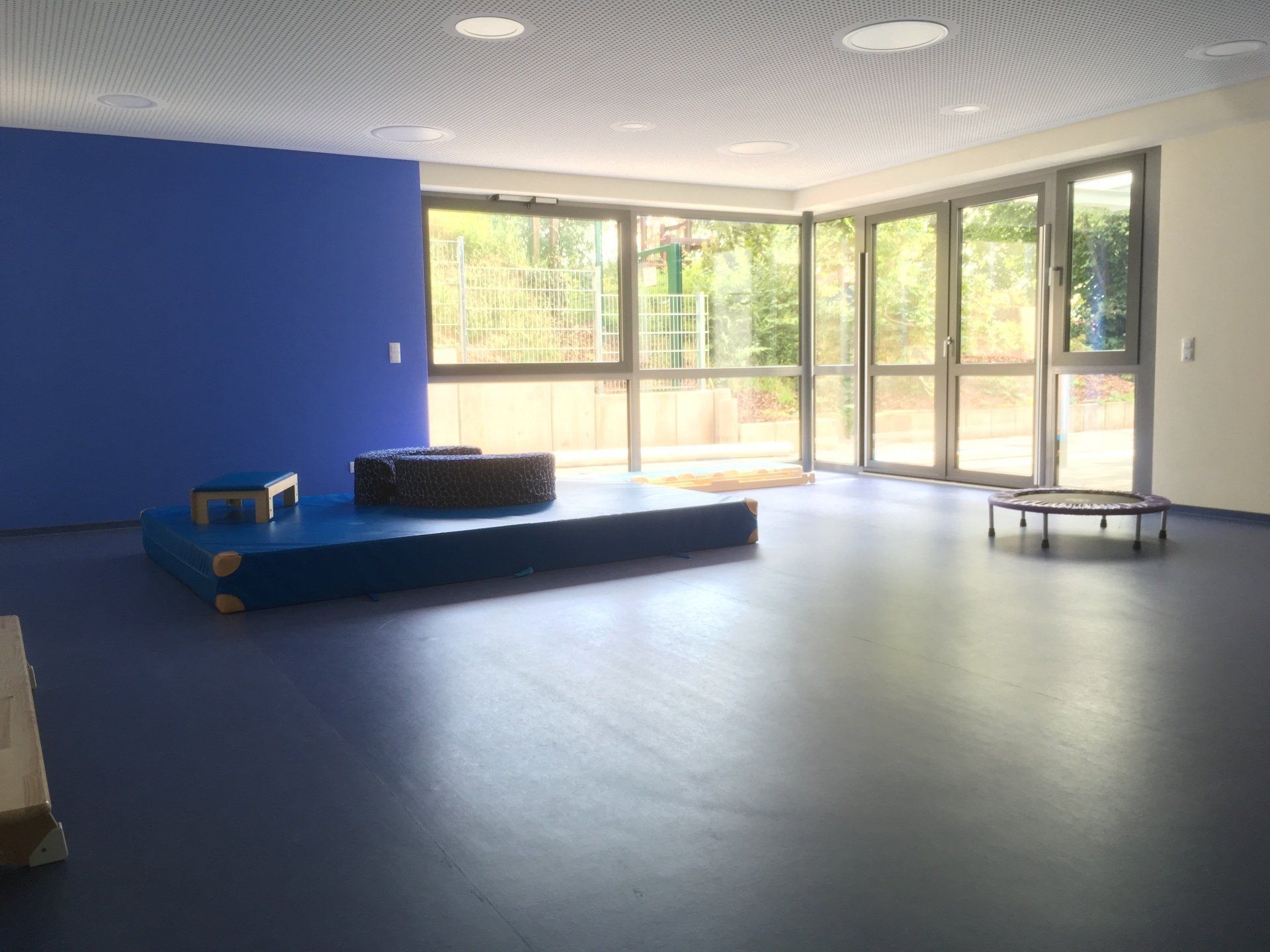 Ein leerer Aktivitätsraum mit blauem Boden, blauer Wand, einer kleinen Bühne mit gepolstertem Sitz 