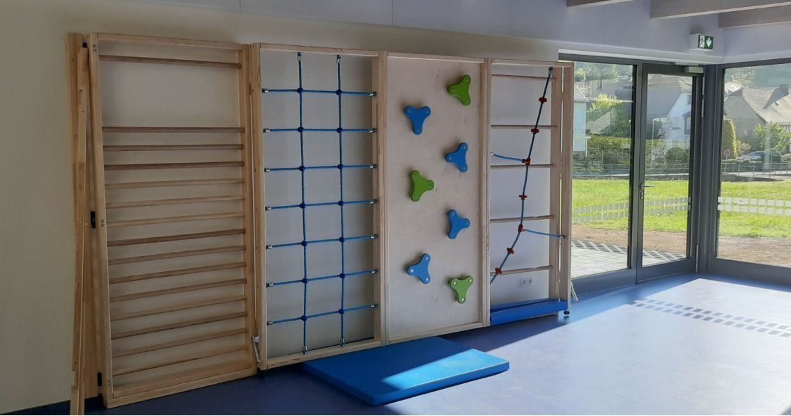 Ein Set aus vier hölzernen Indoor-Trainingswandelementen, bestehend aus einer Kletterwand mit Griffen und einem Kletternetz.