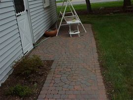 A brick walkway leading to a white house