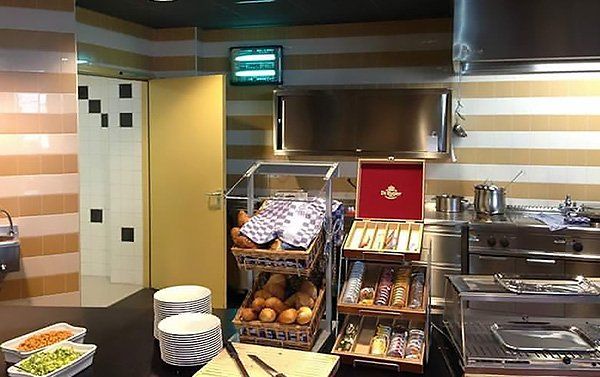 Commercial kitchen with bread display and food prep area, striped walls, metal appliances.