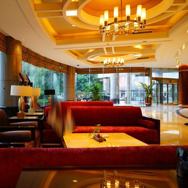 Hotel lobby with red couches, gold ceiling, and large windows.