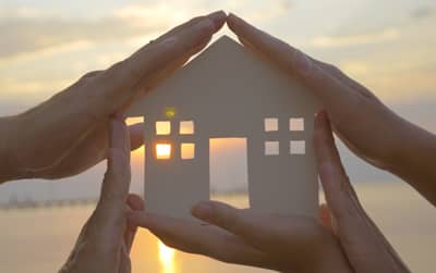 Home cut-out surrounded by hands