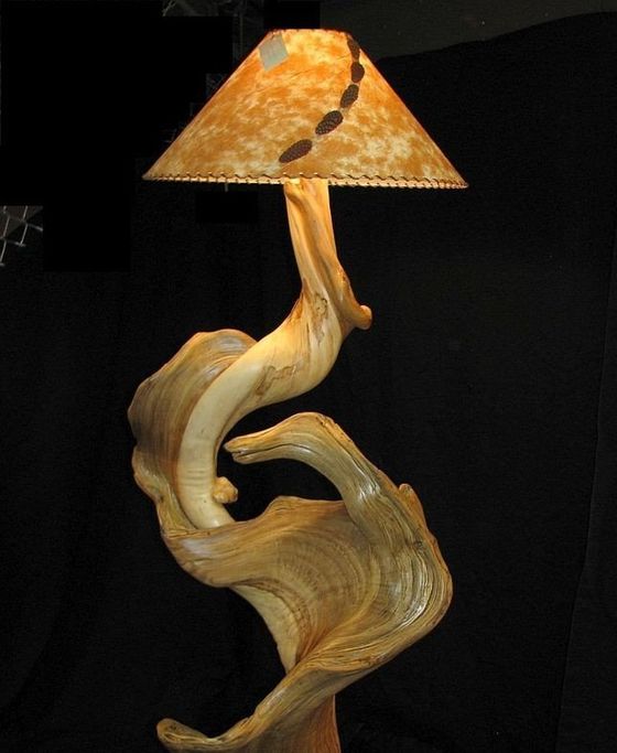 Abstract sculptural lamp with a tan, wavy base and orange patterned shade on a dark background
