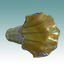 Amber iridescent glass seashell ornament with a ridged, fluted surface on a pale blue background