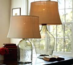 Two glass table lamps with beige shades on a table by a bright window