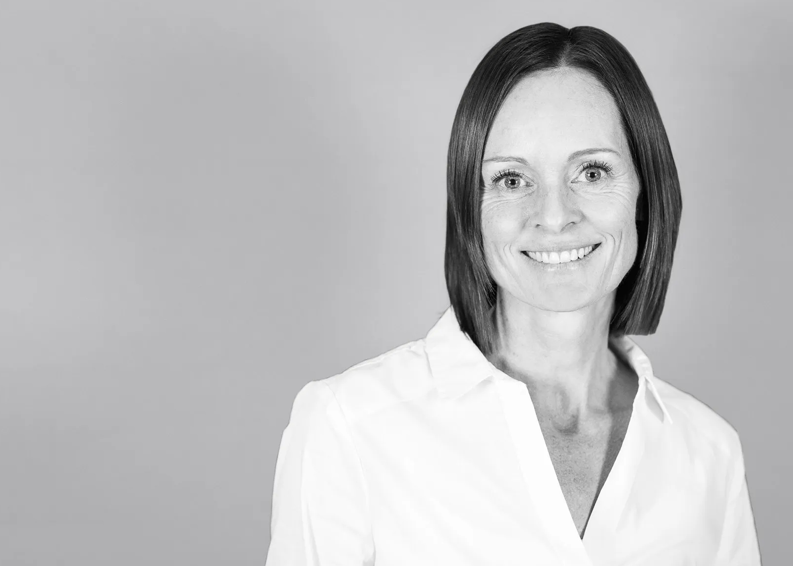 Auf einem Schwarzweißfoto lächelt Nora Giger, MSPhT in einem weißen Hemd.