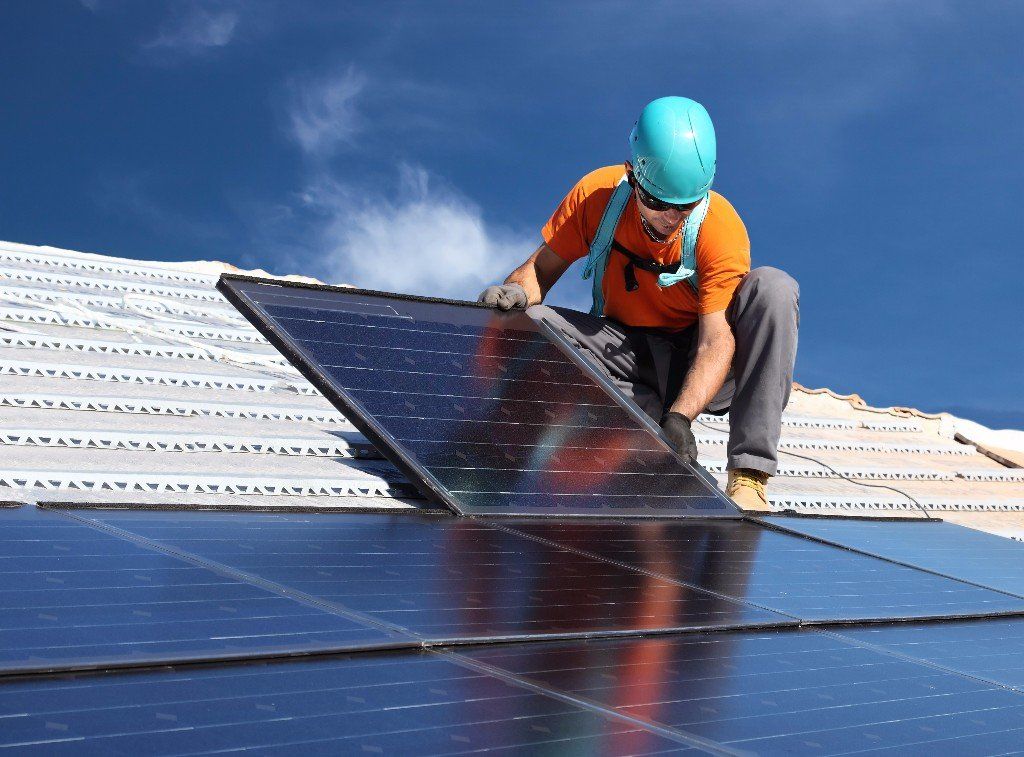 Ein Mann installiert Solarmodule auf einem Dach.