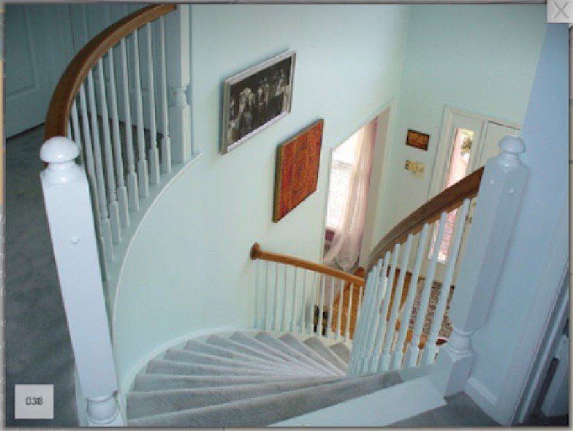 Curved staircase with white railings and light blue walls in a home foyer.