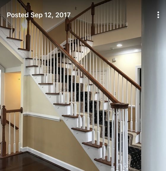 Indoor staircase with wooden handrail, white balusters, and beige walls in a bright home interior