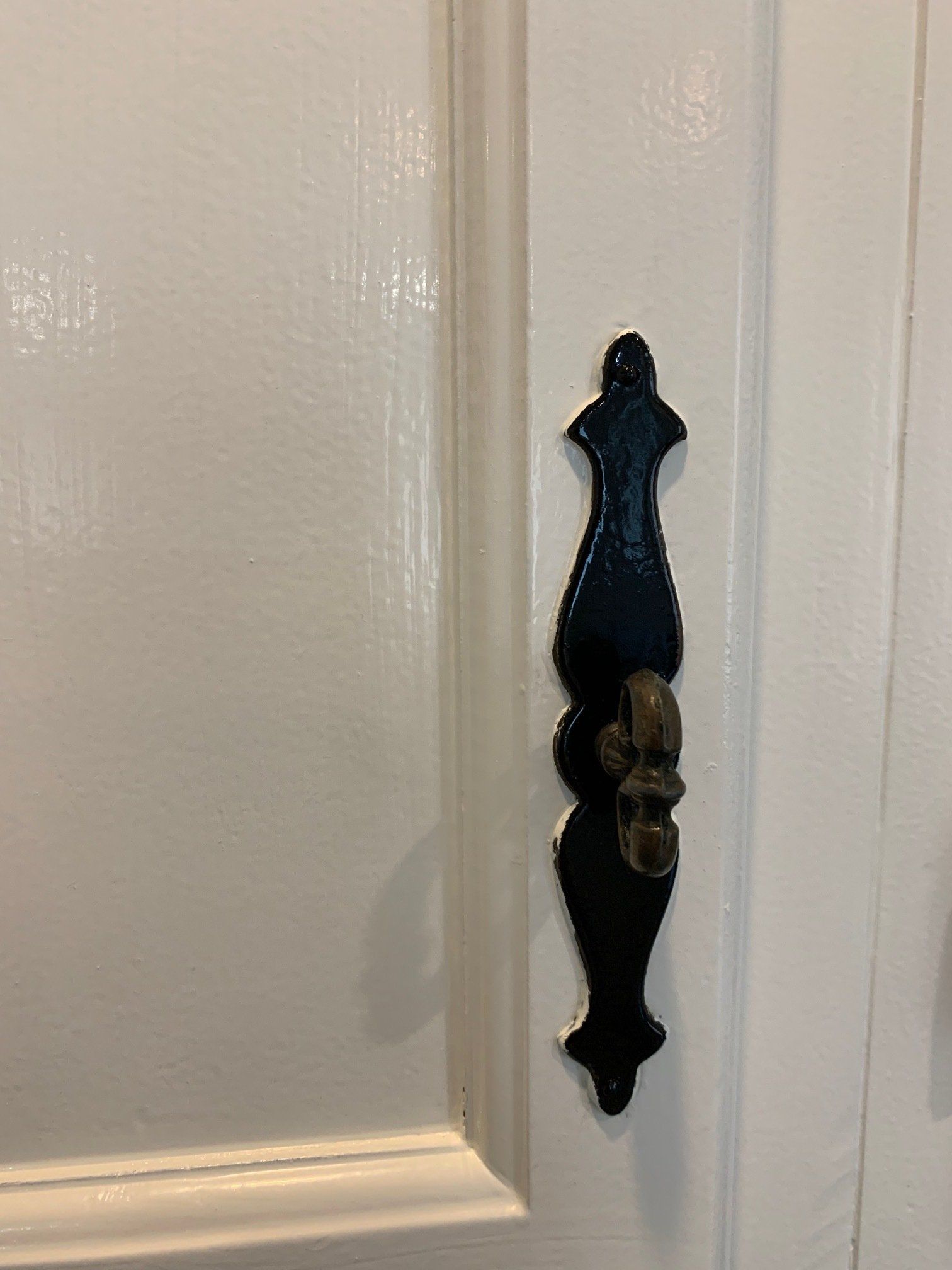 Decorative black door latch on a white paneled door